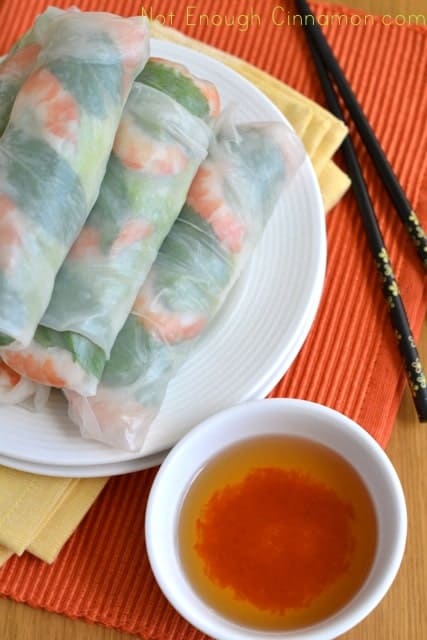 Overhead shot of Vietnamese Spring Rolls on a white plate placed on an orange place mat with chop sticks on the side