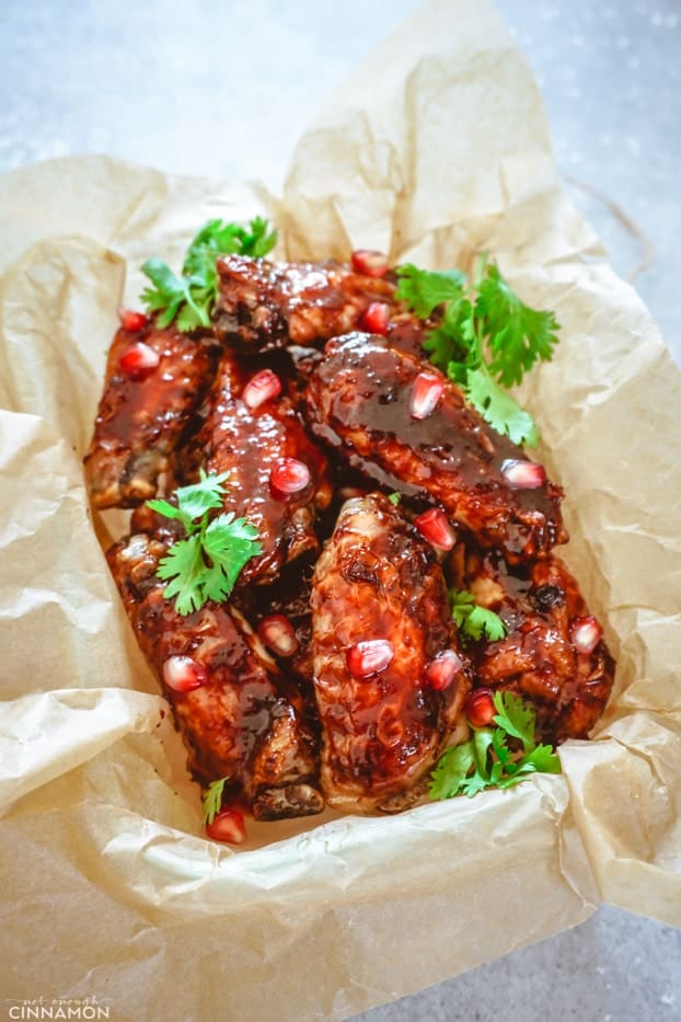 Baked chicken wings with pomegranate glaze in a container with brown paper