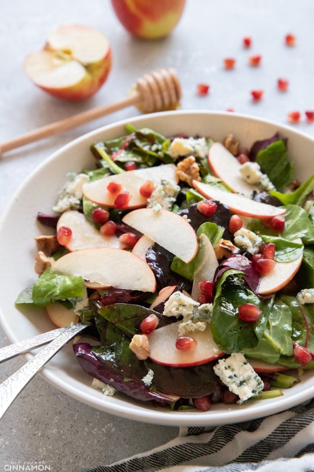 Apple and blue cheese salad in a large salad plate with a serving spoon and fork