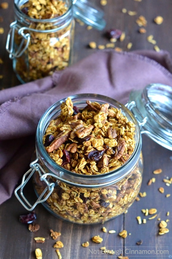 easy homemade pumpkin granola in two mason jars placed on a rustic wooden table with a purple napkin in the background