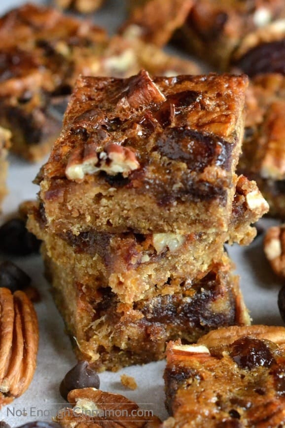 Healthy Pecan Date Bars stacked on top of each other on a baking tray with some whole pecans on the side