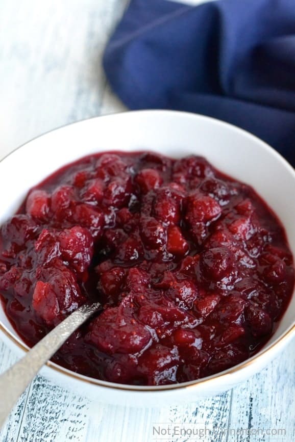 close-up of a white bowl filled with homemade cranberry sauce with orange juice and apples