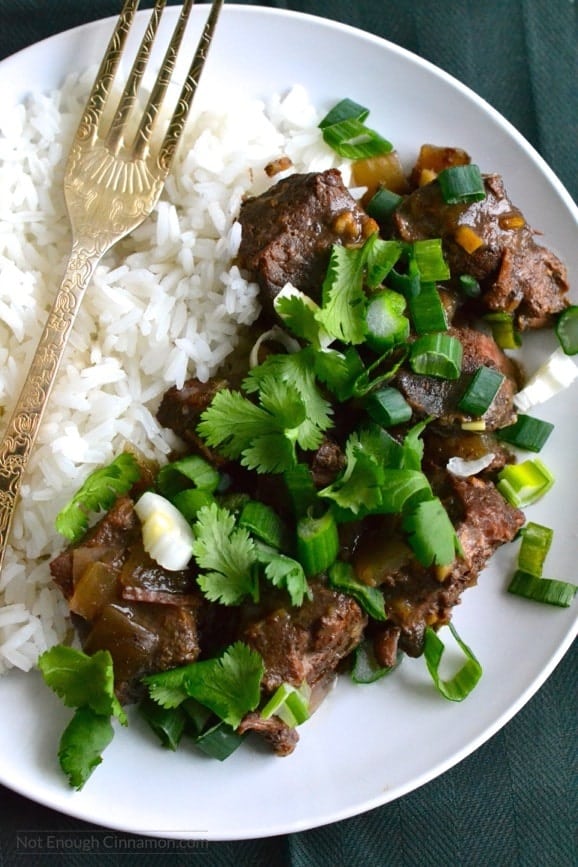 close-up of a plate of slow cooker ginger beef served with a side of rice and some chopped cilantro 