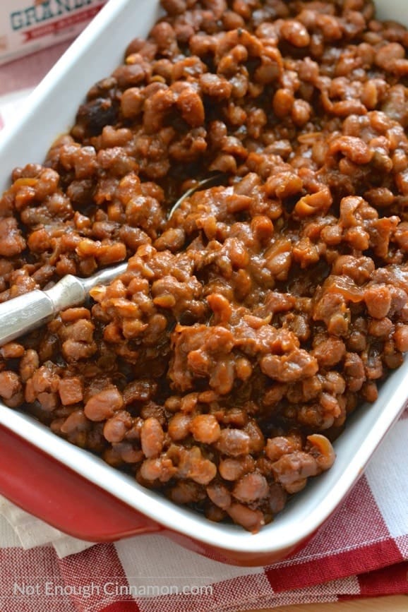 close-up on a casserole with homemade slow cooker baked beans with a spoon on the side