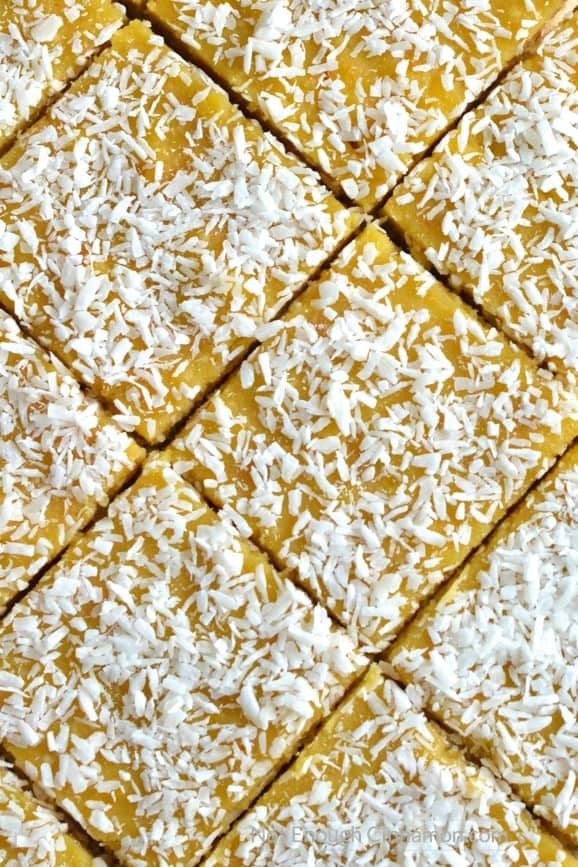 a freshly cut batch of Paleo Coconut Bars with orange curd and shredded coconut on top 