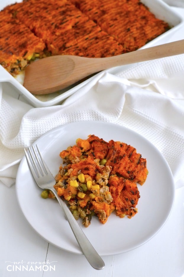 a serving of paleo sweet potato shepherd's pie on a white plate with a casserole dish in the background