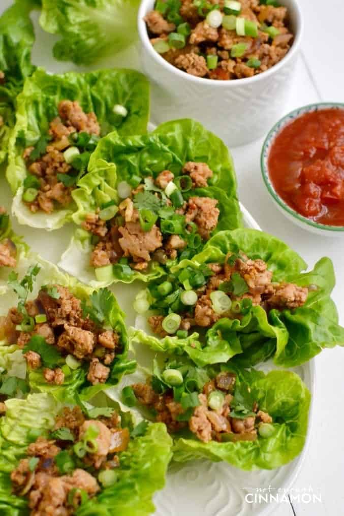 overhead shot of turkey taco lettuce wraps served on a big platter with small side dishes of ground turkey and salsa on the side
