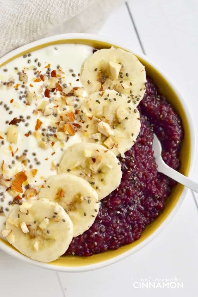 close up of healthy berry quinoa breakfast bowl topped with Greek Yogurt, banana slices and chia seeds