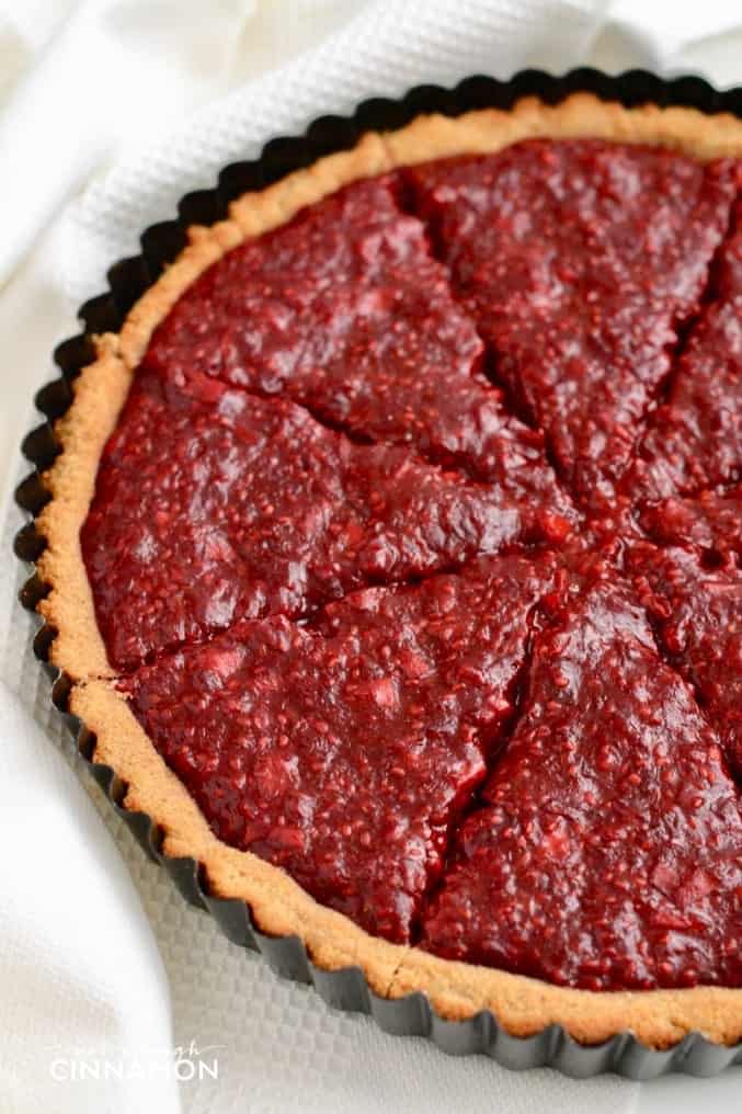 close-up of paleo cinnamon and raspberry tart with paleo coconut flour crust served in a metal tart baking dish