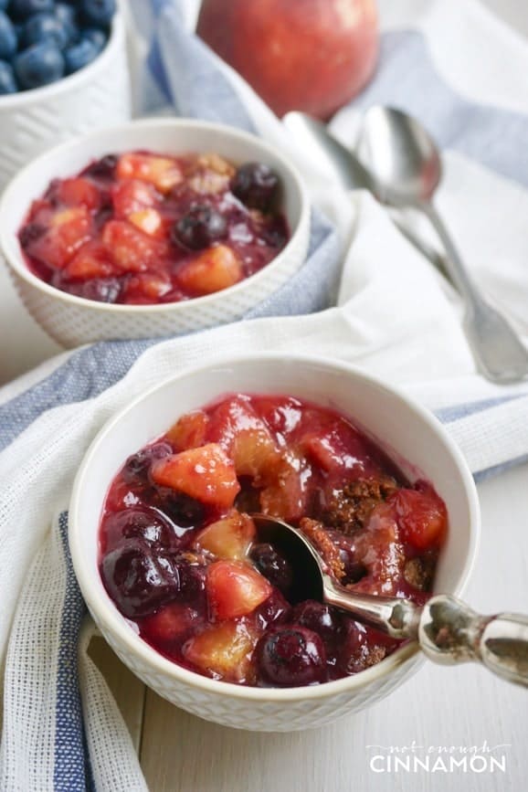 close-up of a small ramekin of peach blueberry cobbler with a spoon inserted