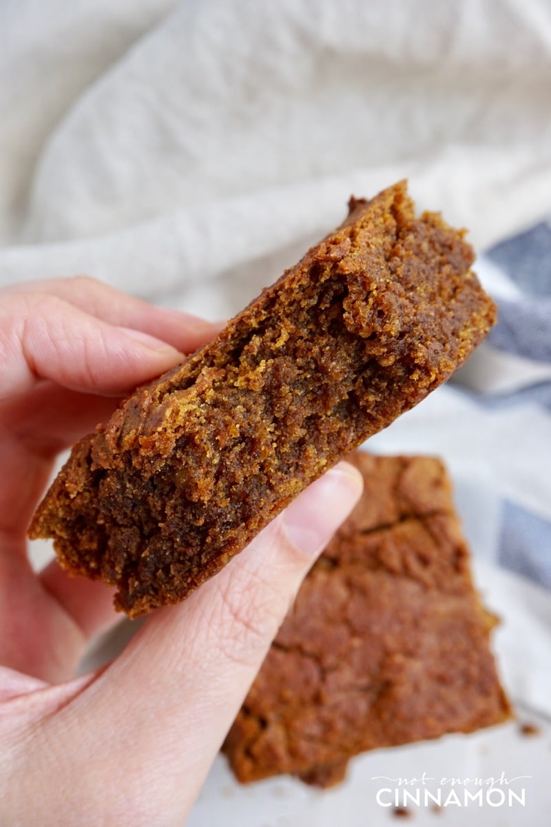 a hand holding a Vegan Paleo Pumpkin Blondie with one bite missing