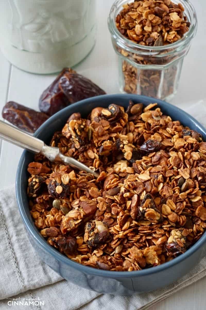 a blue bowl filled with homemade baked honey granola with dates and cashews