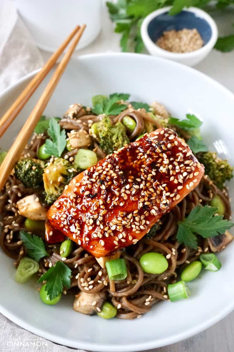 close-up of a maple-glazed salmon fillet on soba noodles, broccoli and edamame beans