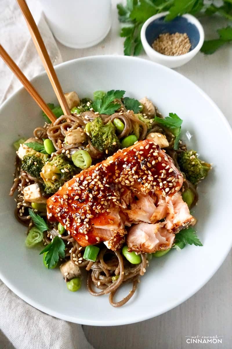 overhead shot of a maple-glazed salmon fillet sprinkled with sesame seeds on a bed of soba noodles and veggies