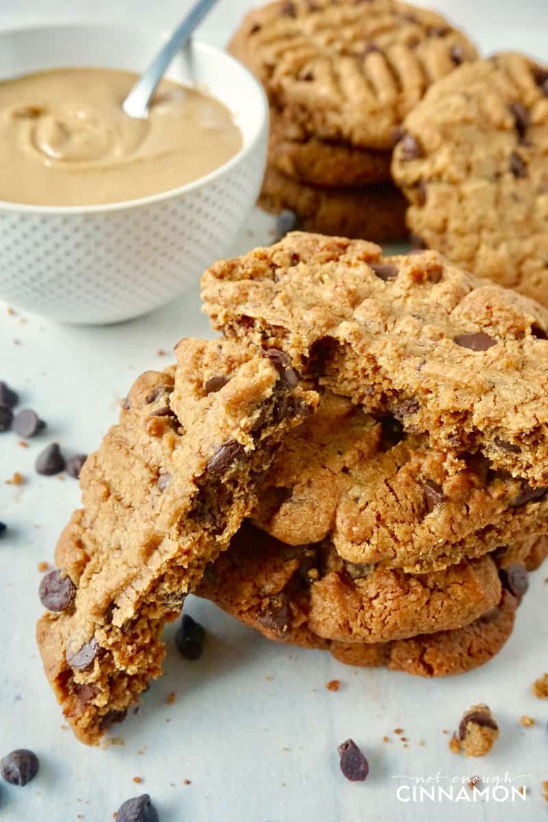Healthier Peanut Butter and Chocolate Cookies with a dish of smooth peanut butter in the background