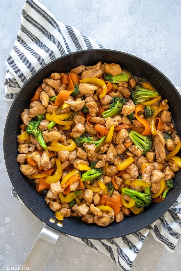 5-Spice Chicken & Vegetable Stir-Fry with homemade chicken stir-fry sauce in a skillet with a kitchen cloth