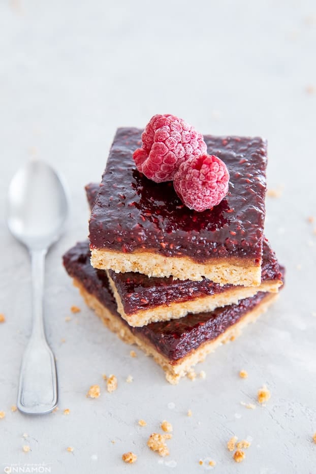 stacked healthy paleo raspberry almond butter bars with a spoon on the side