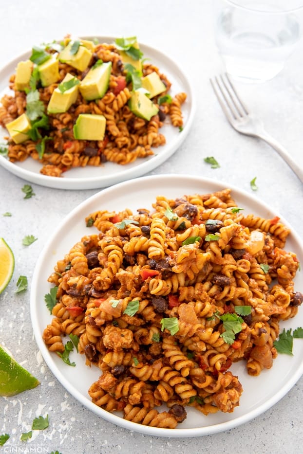 close-up of two servings of one-pot taco pasta loaded with Mexican topping like cilantro and avocado