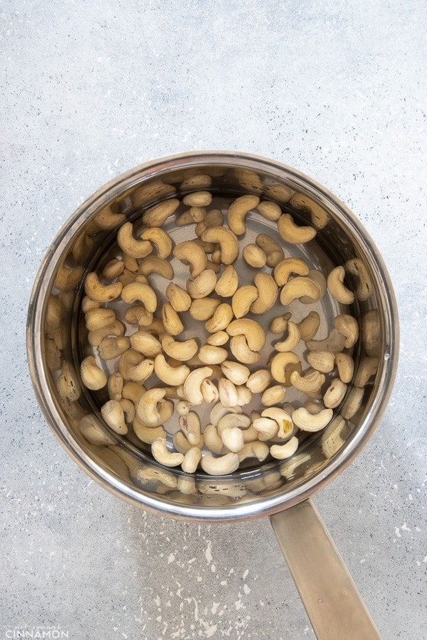 overhead shot of a silver pot with cashew nuts covered with cold water