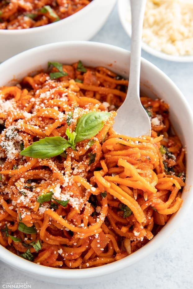  a fork twirling sweet potato spaghetti with tomato sauce in a white pasta bowl