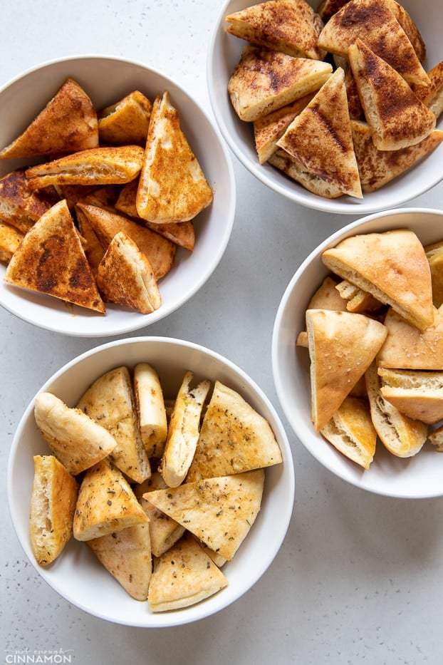 overhead shot of 4 different kinds of homemade pita chips in white bowls