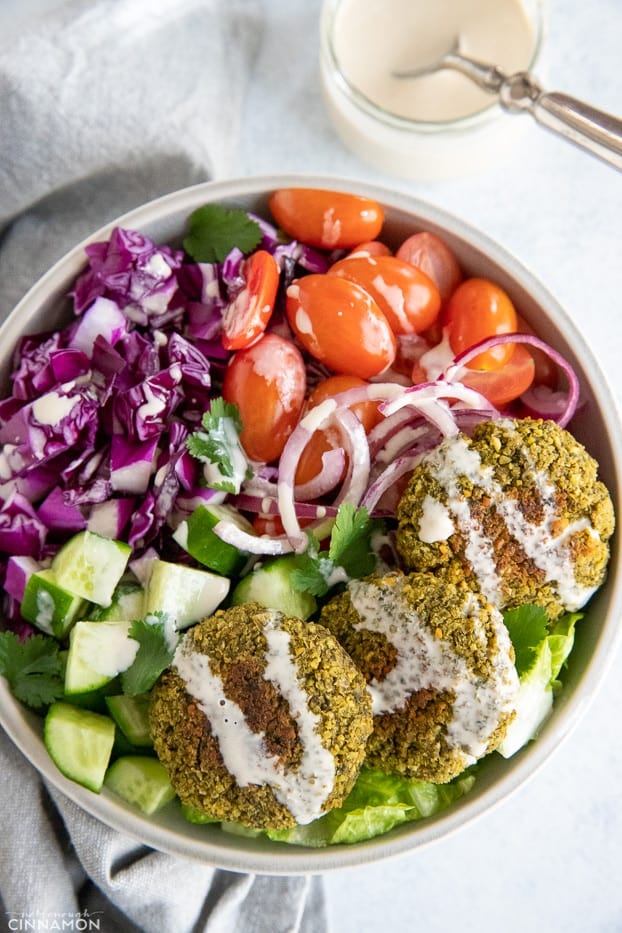 overhead shot of a healthy baked falafel bowl drizzled with tahini sauce