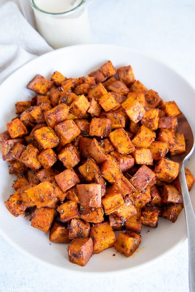 overhead shot of a white bowl with roasted sweet potato cubes with caramelized edges 