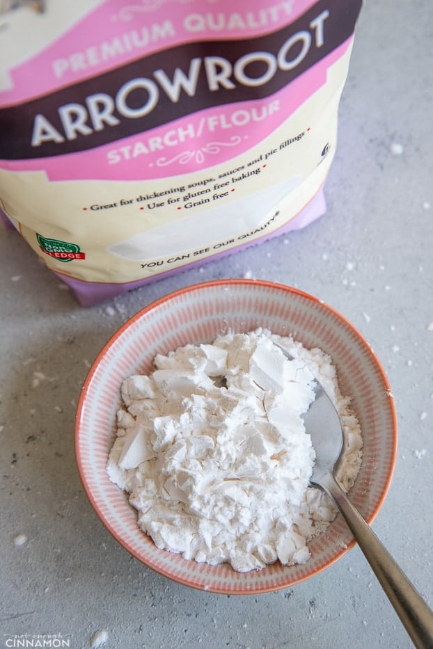 a small bowl of arrowroot starch next to a bag of premium arrowroot powder