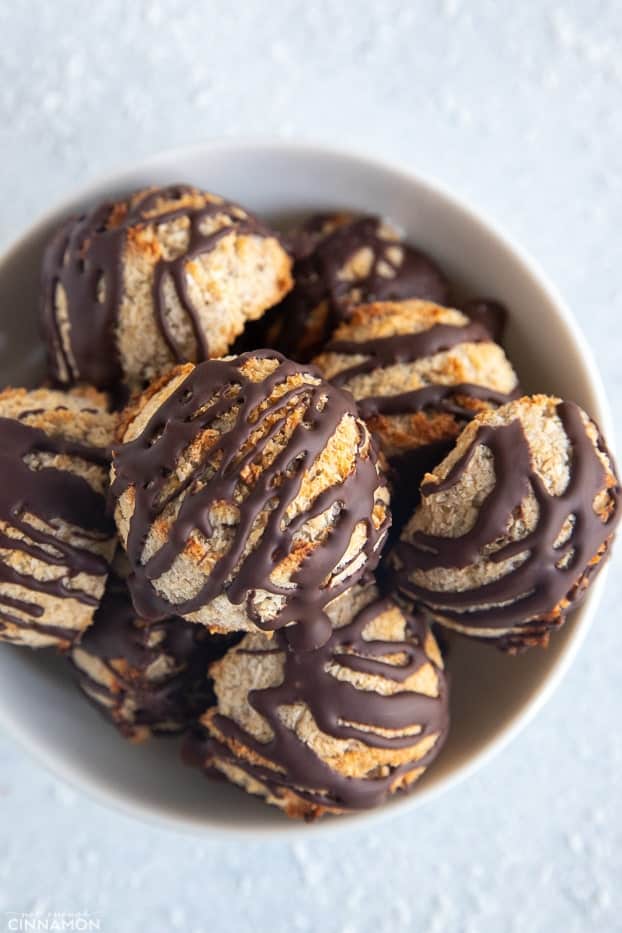 overhead shot of a bowl of healthy vegan coconut macaroons drizzled with dark chocolate