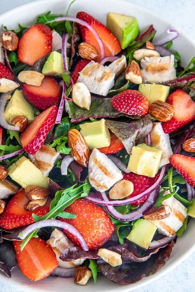 overhead shot of healthy chicken salad with candied almonds, avocado and strawberries