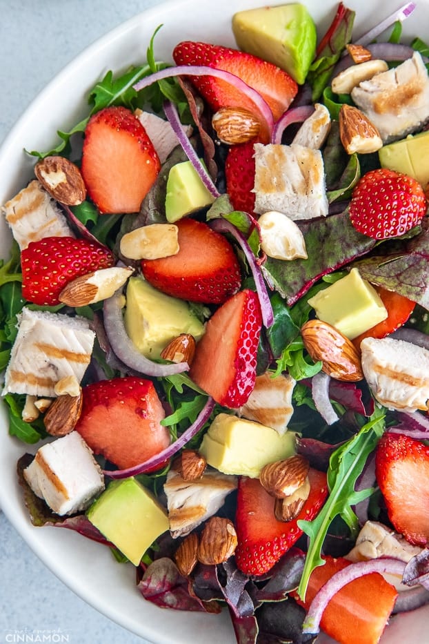 overhead shot of a healthy chicken salad with candied almonds, strawberries and avocado