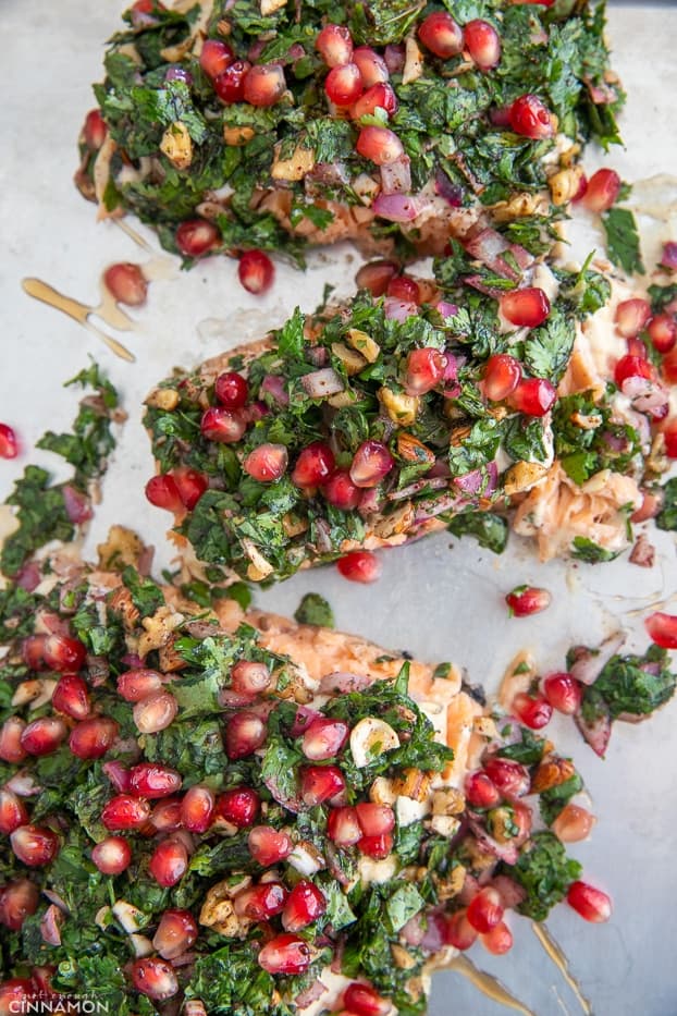 overhead shot of salmon fillets topped with fresh herbs and pomegranate seeds