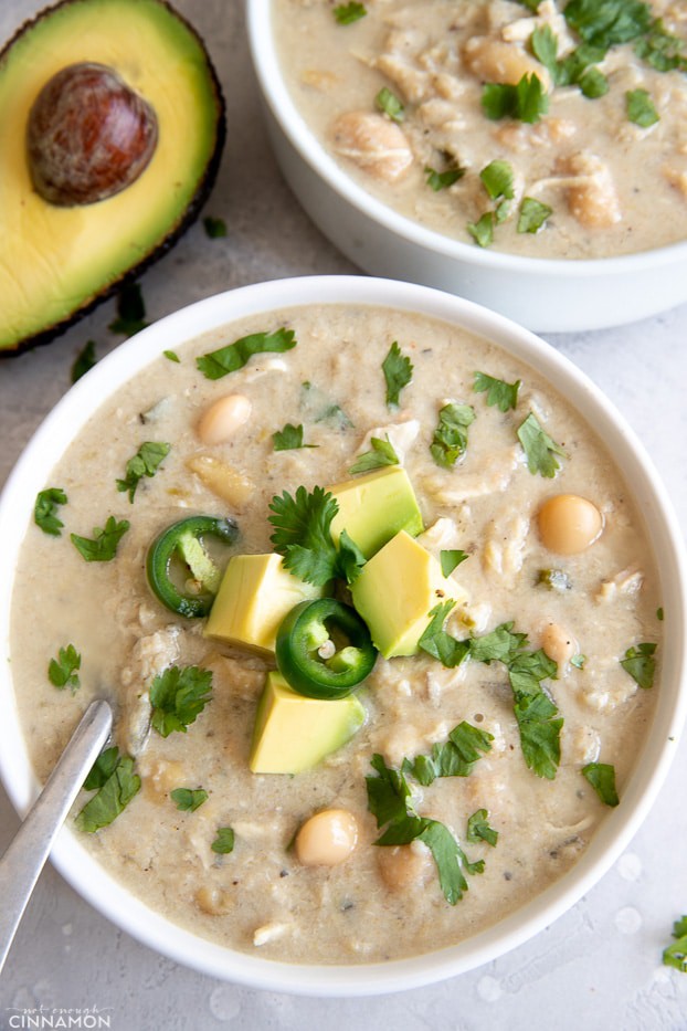 overhead shot of a bowl of slow cooker white chicken chili topped with avocado and cilantro leaves