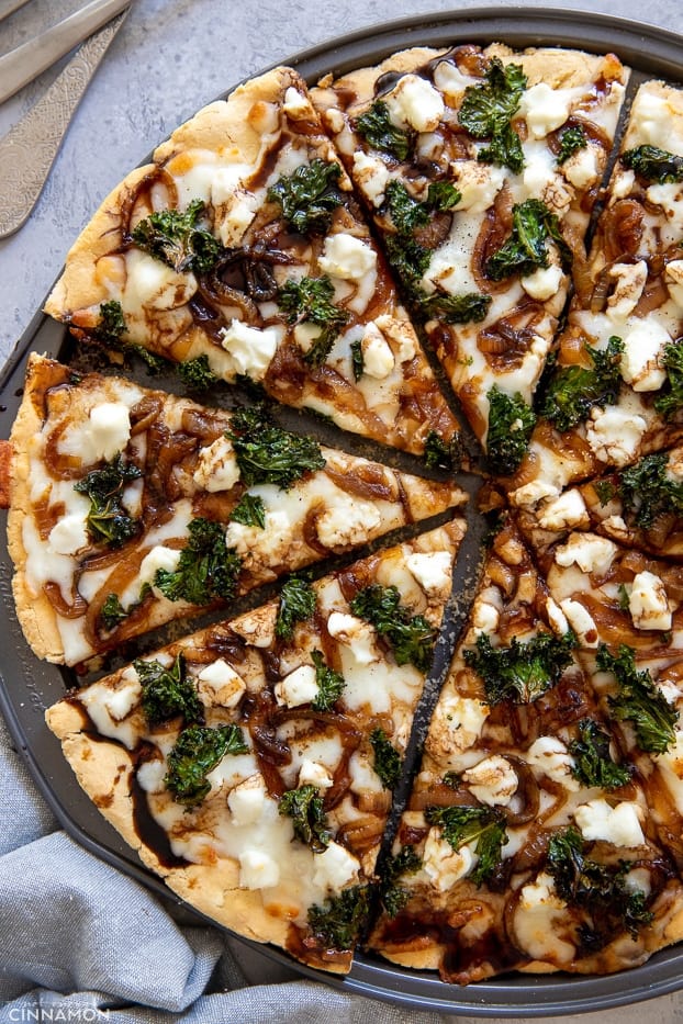 overhead shot of a gluten-free goat cheese and kale pizza drizzled with balsamic glaze