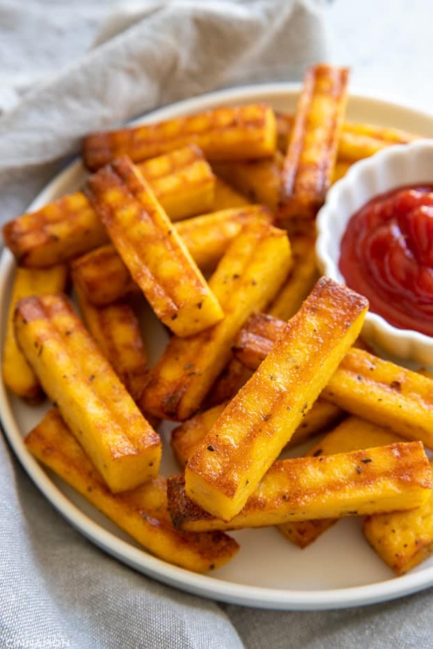 side views of a plate of healthy cheesy and crispy baked polenta fries with ketchup 