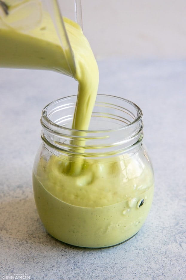 creamy avocado ranch dressing being poured into a small mason jar