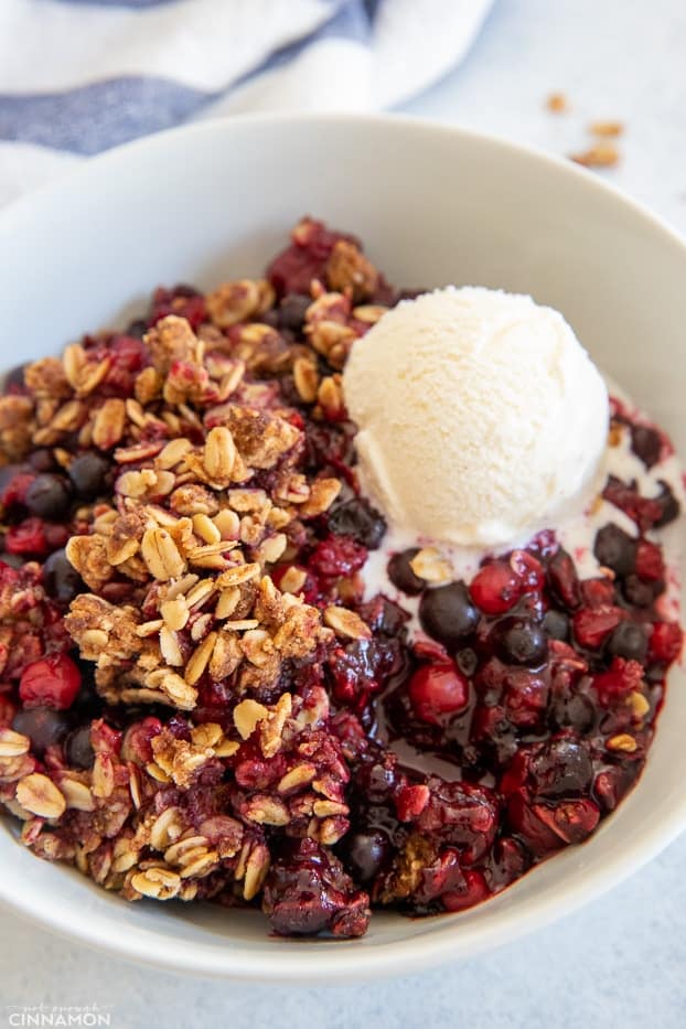 overhead shot of a serving of healthy berry crisp served with a scoop of vanilla ice cream 