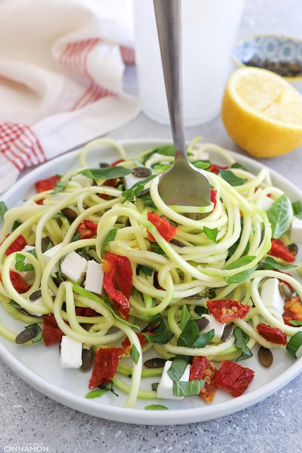 a plate of Mediterranean spiralized zucchini salad with a fork twirling the noodles
