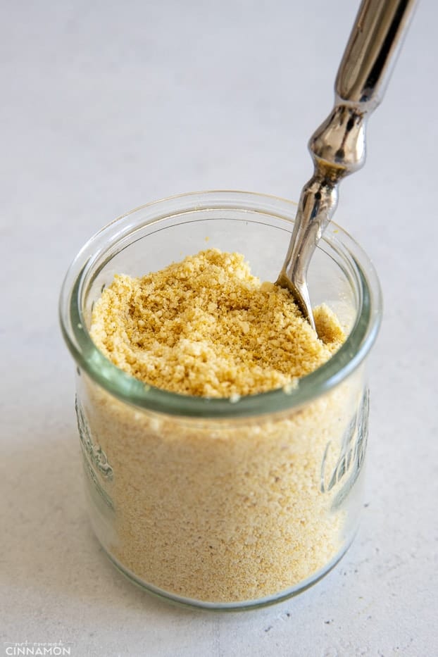 side view of a small glass jar filled with vegan parmesan cheese 