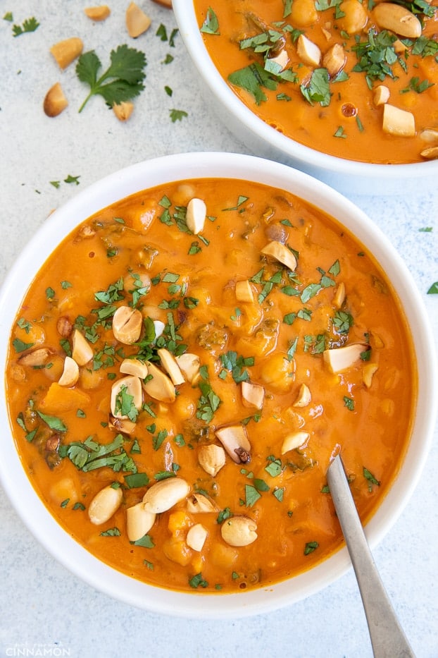 a bowl of African Peanut Soup with chickpeas and vegetables with a soup spoon inserted