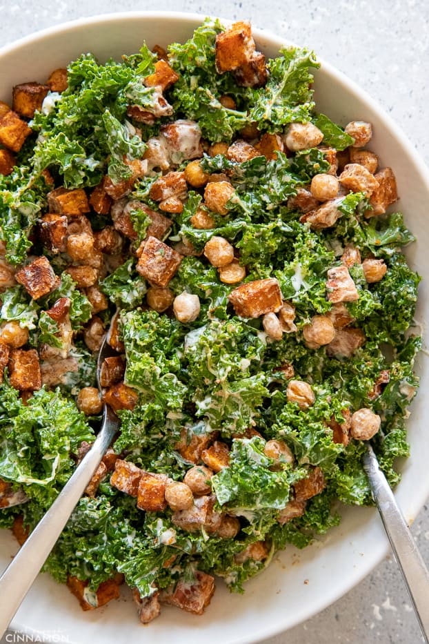 roasted chickpea sweet potato salad with kale being tossed with creamy Greek yogurt dressing 