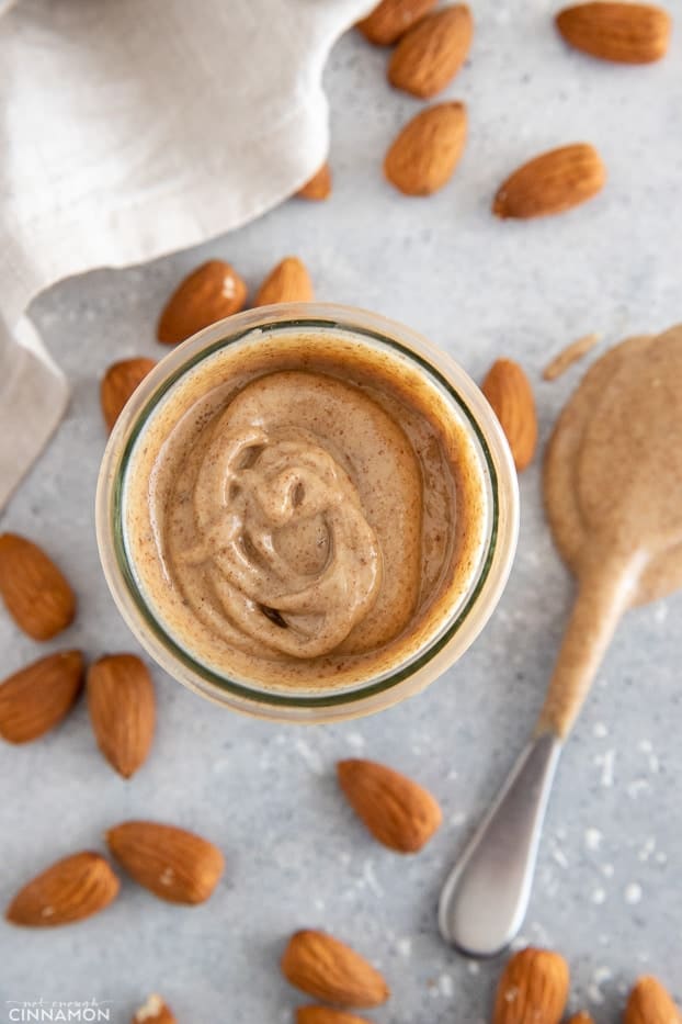 overhead shot of a small jar with homemade almond butter with almonds on the side