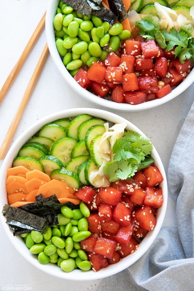 overhead shot of two watermelon tuna vegan poke bowls with chopsticks on the side 