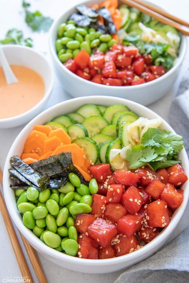 two vegan poke bowls with edamame beans, nori and watermelon tuna served with a side dish of mayo