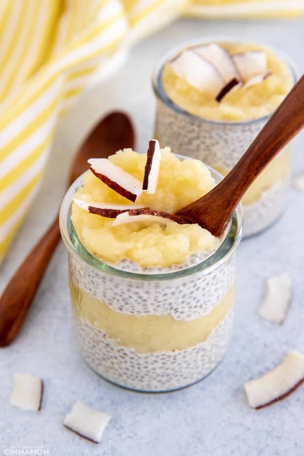 a wooden spoon being dipped into a small jar with pina colada chia pudding