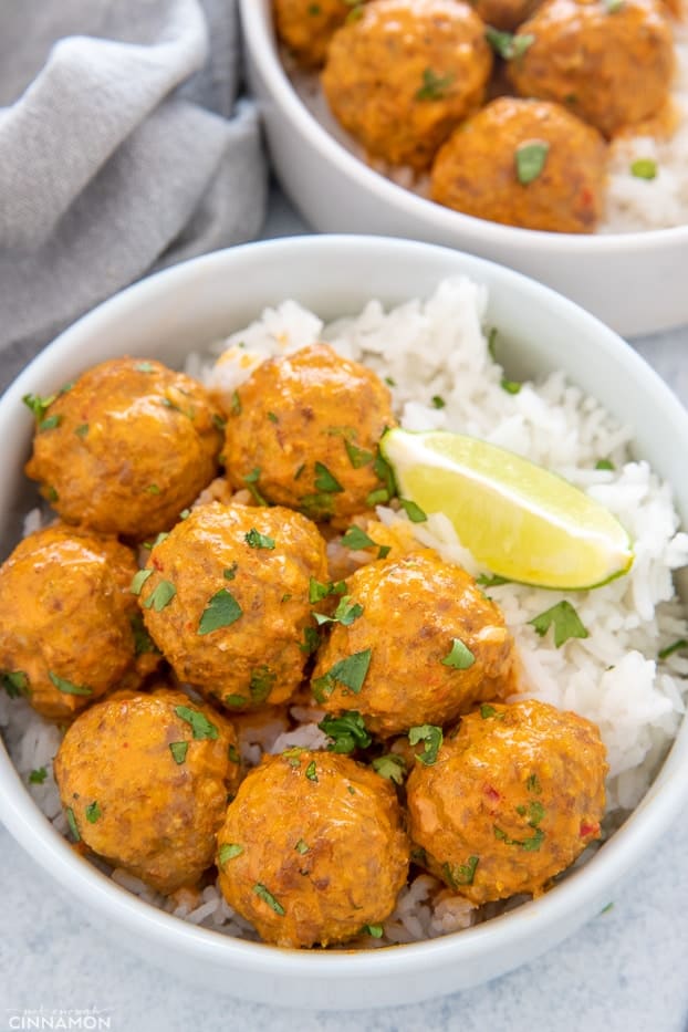 close-up of a serving of thai turkey meatballs served with a side of rice and lime wedges