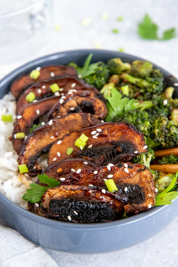 glazed teriyaki mushrooms served on rice in a bowl with chopsticks on the side