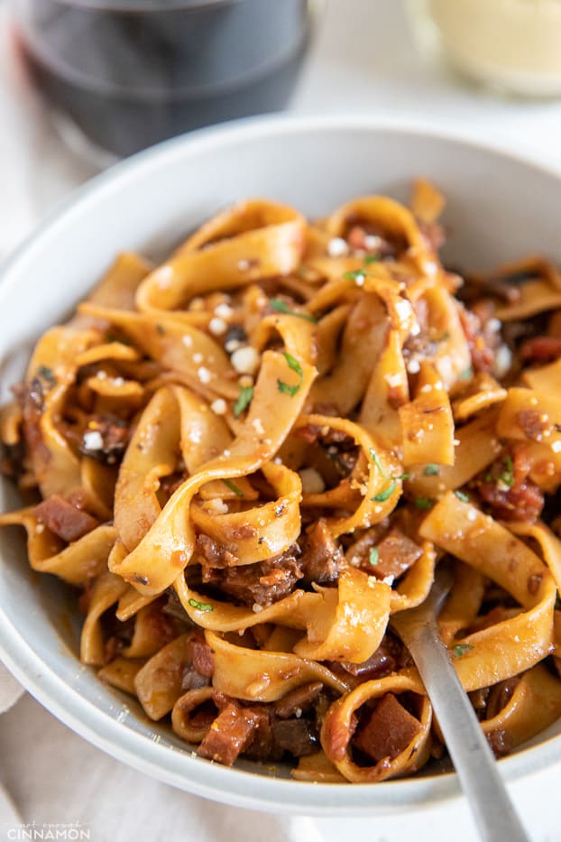 a fork twirling fettuccine pasta with mushroom bolognese and vegan parmesan 