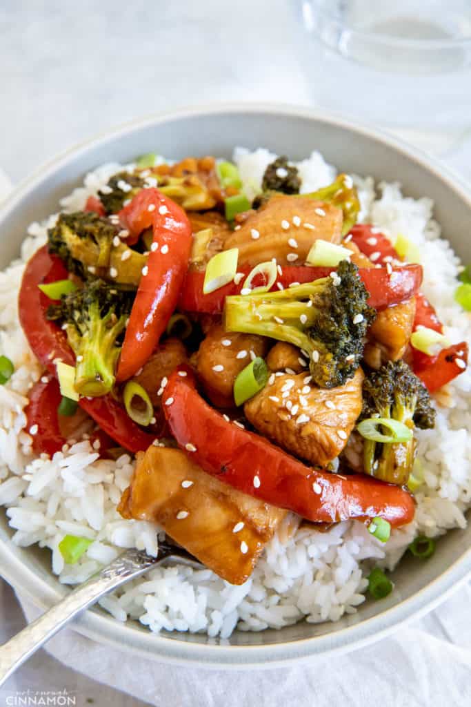 healthy hot honey chicken stir-fry with broccoli and pepper served over rice sprinkled with sesame seeds