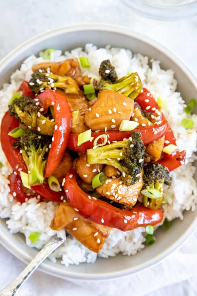 healthy hot honey chicken stirfry with bell pepper, broccoli and sweet hot honey sauce served in a bowl over rice